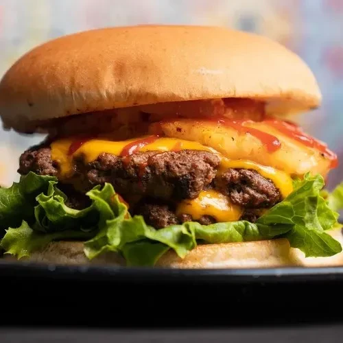 Gourmet burger with two beef patties, melted cheese, and pineapple.