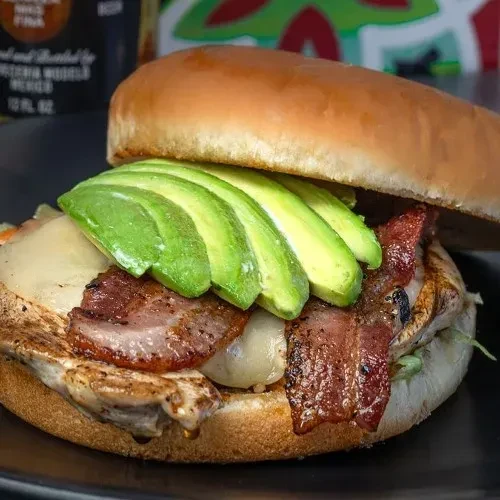 Grilled chicken sandwich with melted cheese, crispy bacon, avocado.