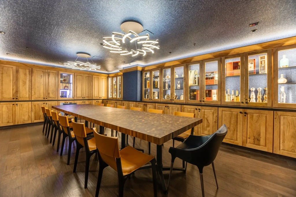 Private dining room with long wooden table and illuminated beverage cabinets.