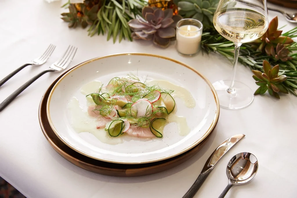 Fish carpaccio with cucumber, radish, and dill on an elegant table.