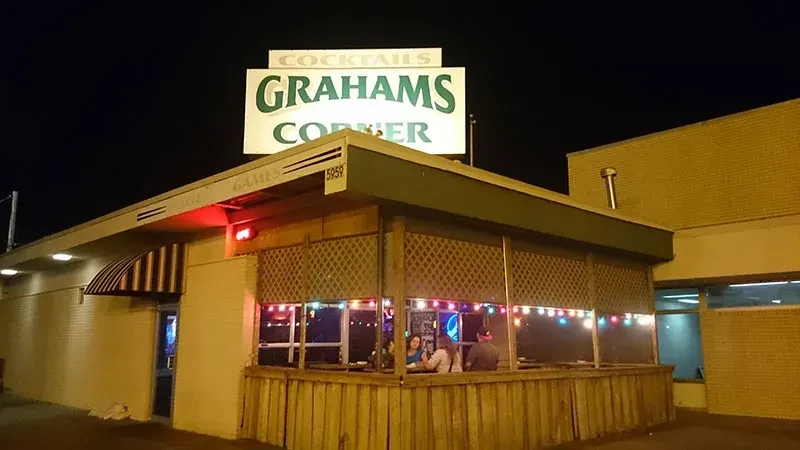 Night exterior of Grahams Corner bar, lit by string lights.