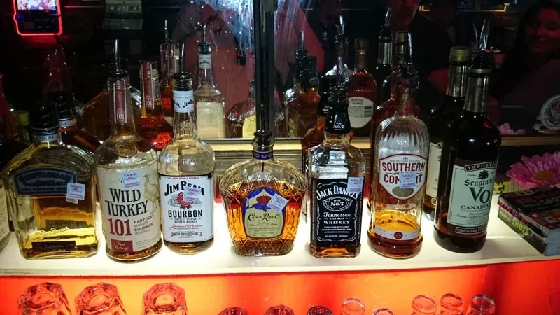 Close-up of a backlit bar shelf with various liquor bottles and glasses.
