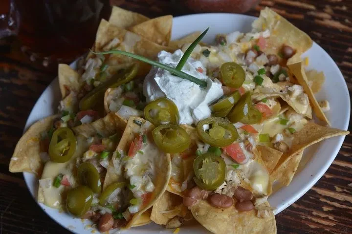 Close-up: Loaded nachos with cheese, meat, beans, sour cream, and jalapeños.