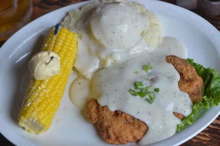 Overhead shot of fried steak, mashed potatoes, gravy, and buttered corn.