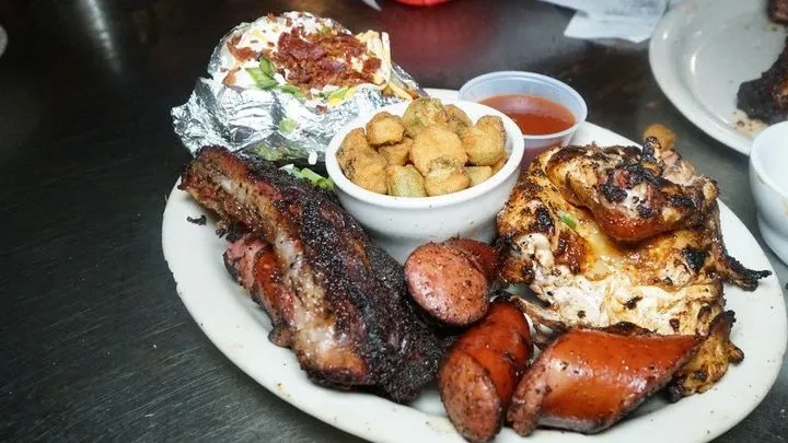 Platter of barbecued ribs, sausage, chicken, okra, potato, and sauce.