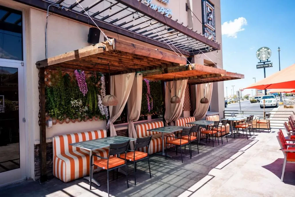 Bright outdoor patio with orange seating, green wall, and pergola.