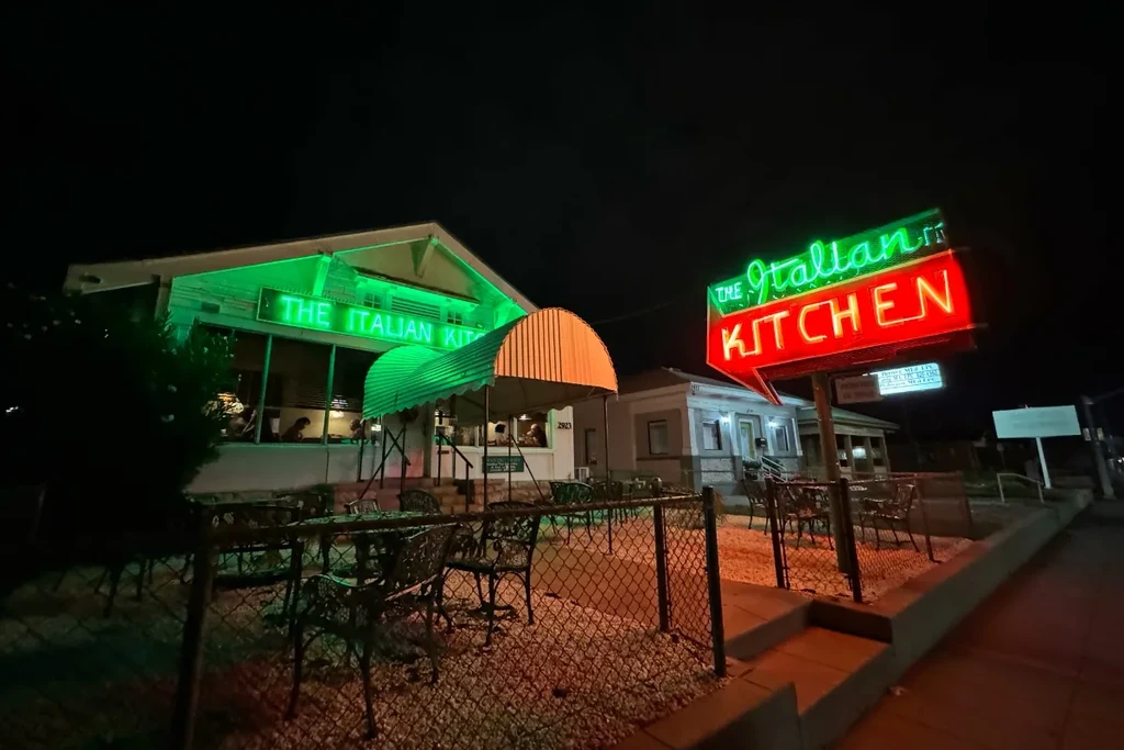 The Italian Kitchen restaurant at night, illuminated by green and red neon.