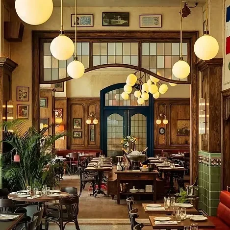 Empty restaurant interior, dark wood, set tables, prominent blue door.