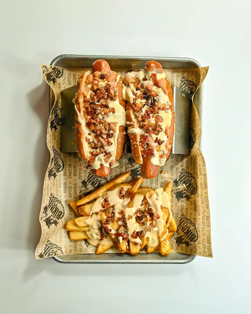 Two loaded hot dogs and fries with creamy sauce and crispy toppings.