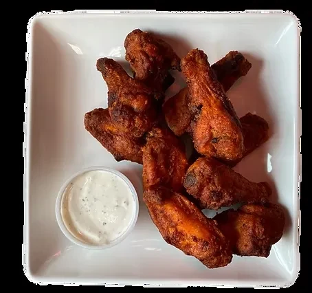Seven golden-brown fried chicken wings with herb dipping sauce.