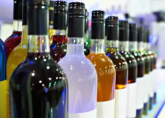 Row of uniformly lined glass bottles containing various colorful liquids.