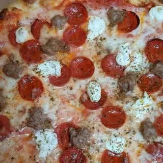 Freshly baked pizza with pepperoni, sausage, ricotta, and green herbs.