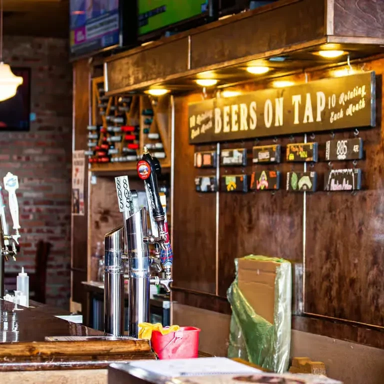 Shiny beer taps and "BEERS ON TAP" sign on a bar counter.