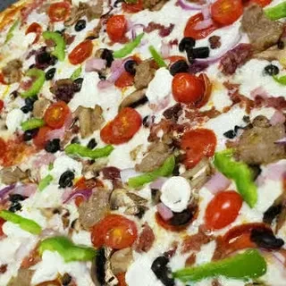 Close-up pizza with tomatoes, bell peppers, olives, red onions, and meat.