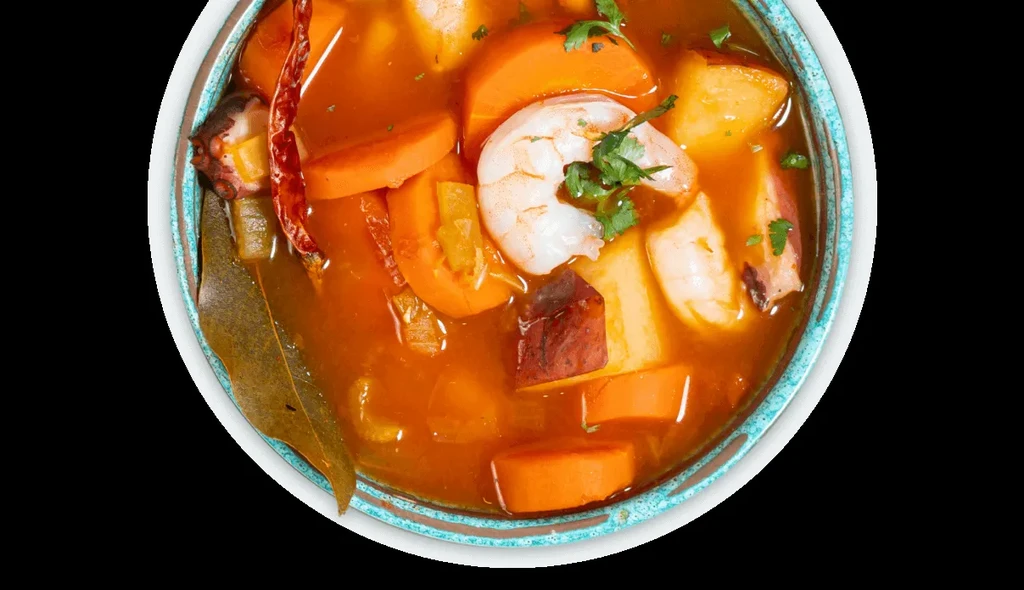 Colorful seafood and vegetable stew with shrimp and red broth.