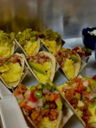 A tray of neatly arranged small tacos with diverse fillings.