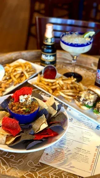 Table spread with chips, dip, fries, sliders, beer, and margarita.