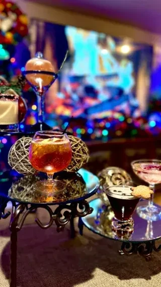 Festive cocktails on tiered mirror stands with blurred colorful lights.