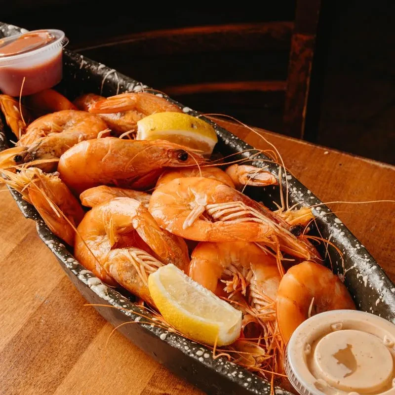 Cooked orange shrimp platter with lemon wedges and two sauces.