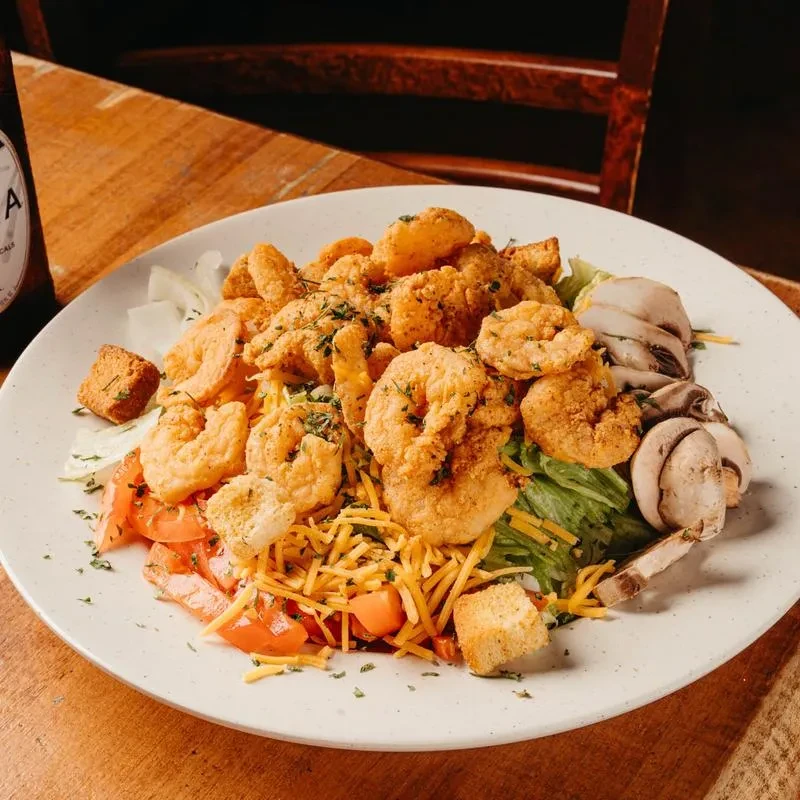 Fried shrimp salad with lettuce, tomatoes, cheese, croutons, and mushrooms.