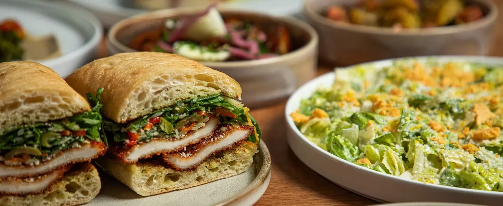 Half-cut focaccia sandwich with breaded cutlet and a Caesar salad.