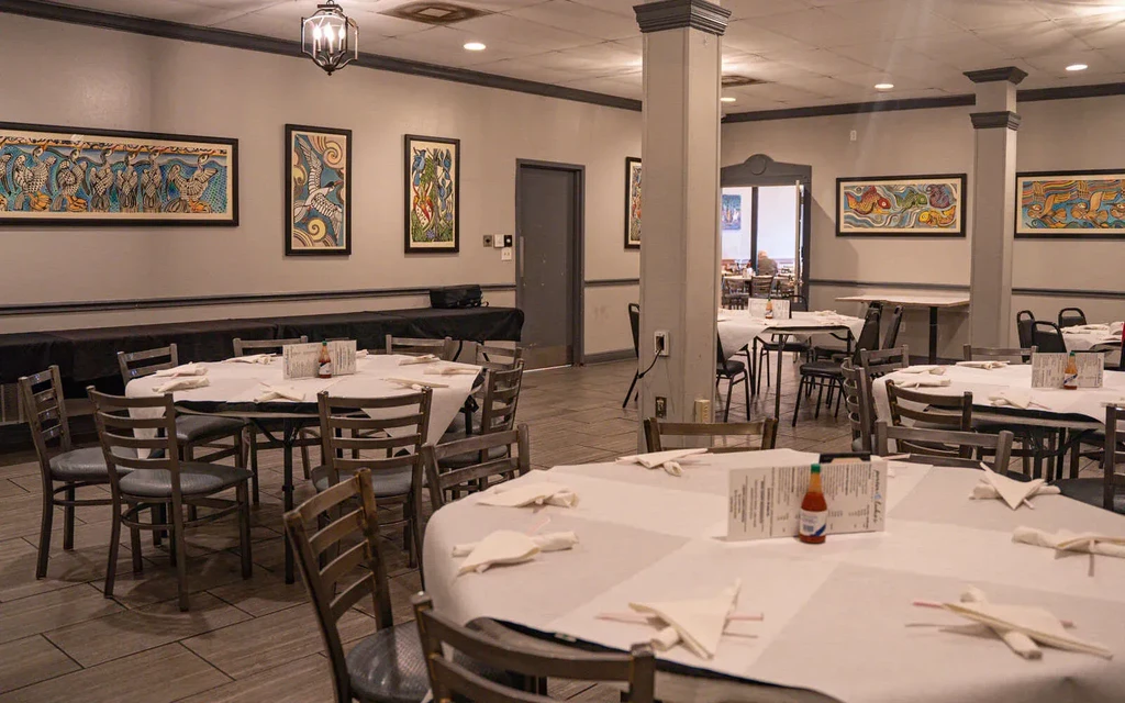 Empty, well-lit restaurant dining room with set tables and colorful art.