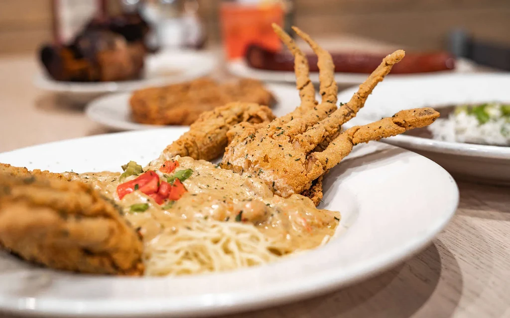 Crispy soft-shell crab on pasta with creamy sauce and vegetables.