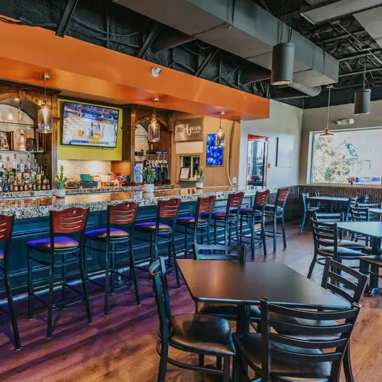 Empty modern restaurant interior with a bar and dining tables.