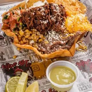 Taco salad in edible tortilla bowl with shredded meat, beans, rice.