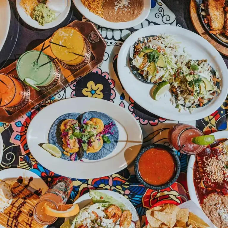 Overhead view of a table full of colorful Mexican food and drinks.