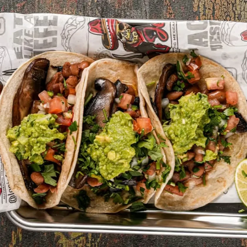 Three vegetarian tacos with mushrooms, beans, pico, and guacamole.