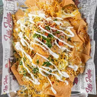 Overhead view of large nachos with melted cheese, jalapeños, salsa, sour cream.