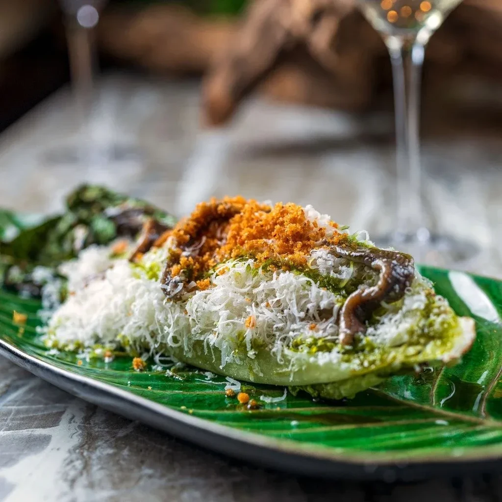 Half-cut lettuce with cheese, pesto, anchovies, and orange crumbs.