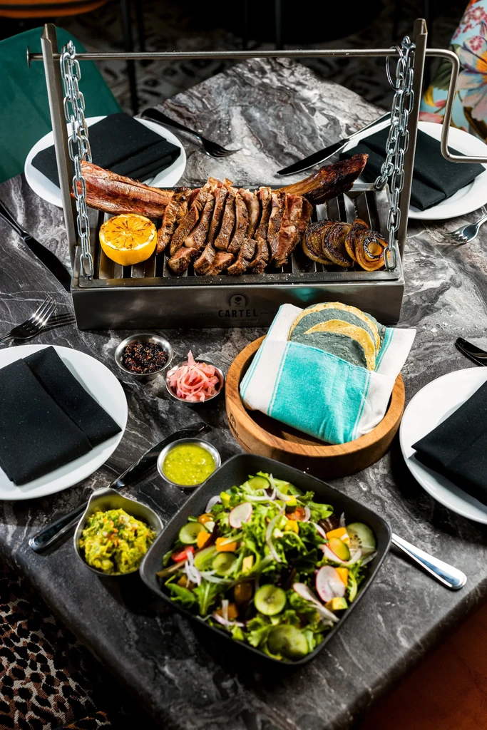 A vibrant spread of sliced steak, tortillas, and diverse side dishes.
