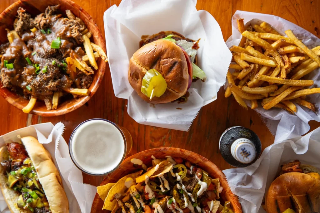 Overhead shot of burgers, poutine, nachos, hot dog, and beer.