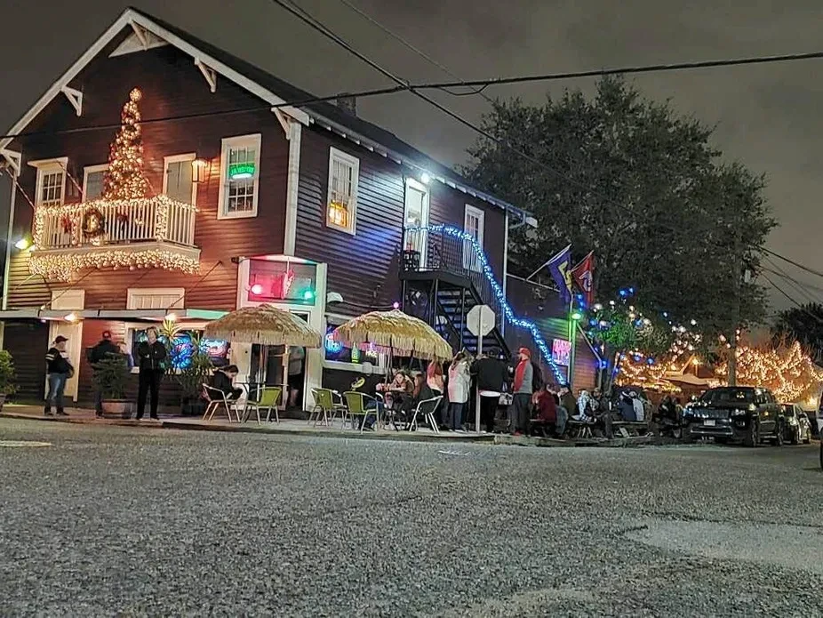 Two-story restaurant brightly lit with Christmas lights and people dining outdoors.