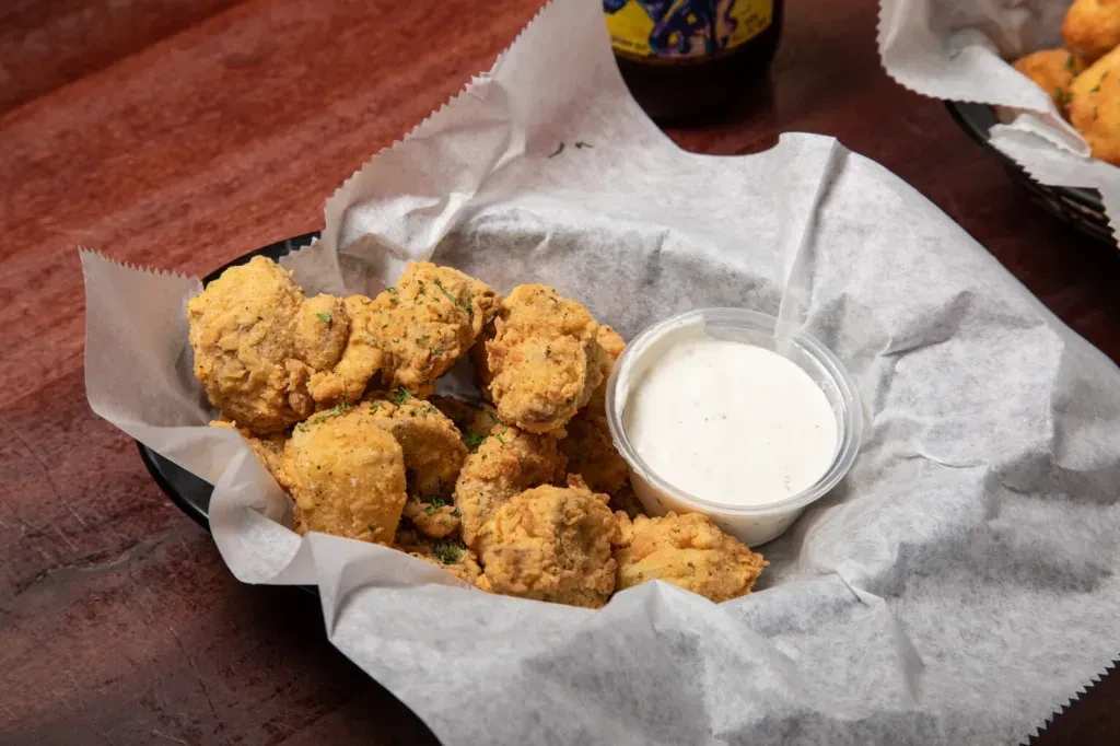 Crispy golden-brown fried food in a basket with dipping sauce.