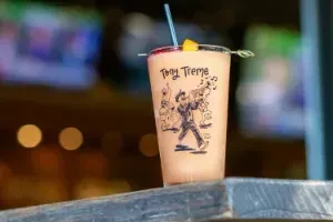 Frozen brown drink with fruit garnish and saxophone character art on cup.