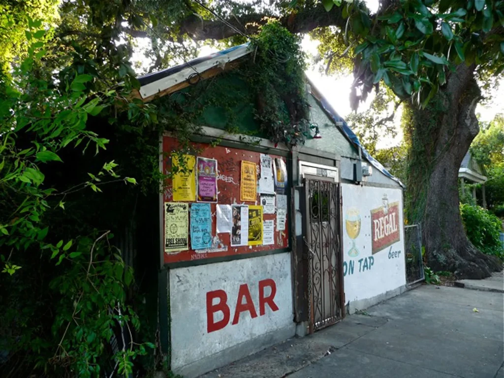 Rustic bar exterior with painted "BAR" sign and "REGAL BEER" advertisement.