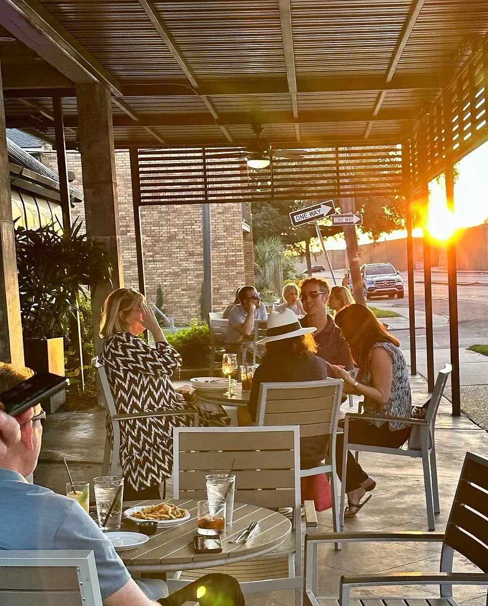 Covered outdoor patio with guests at tables during golden sunset