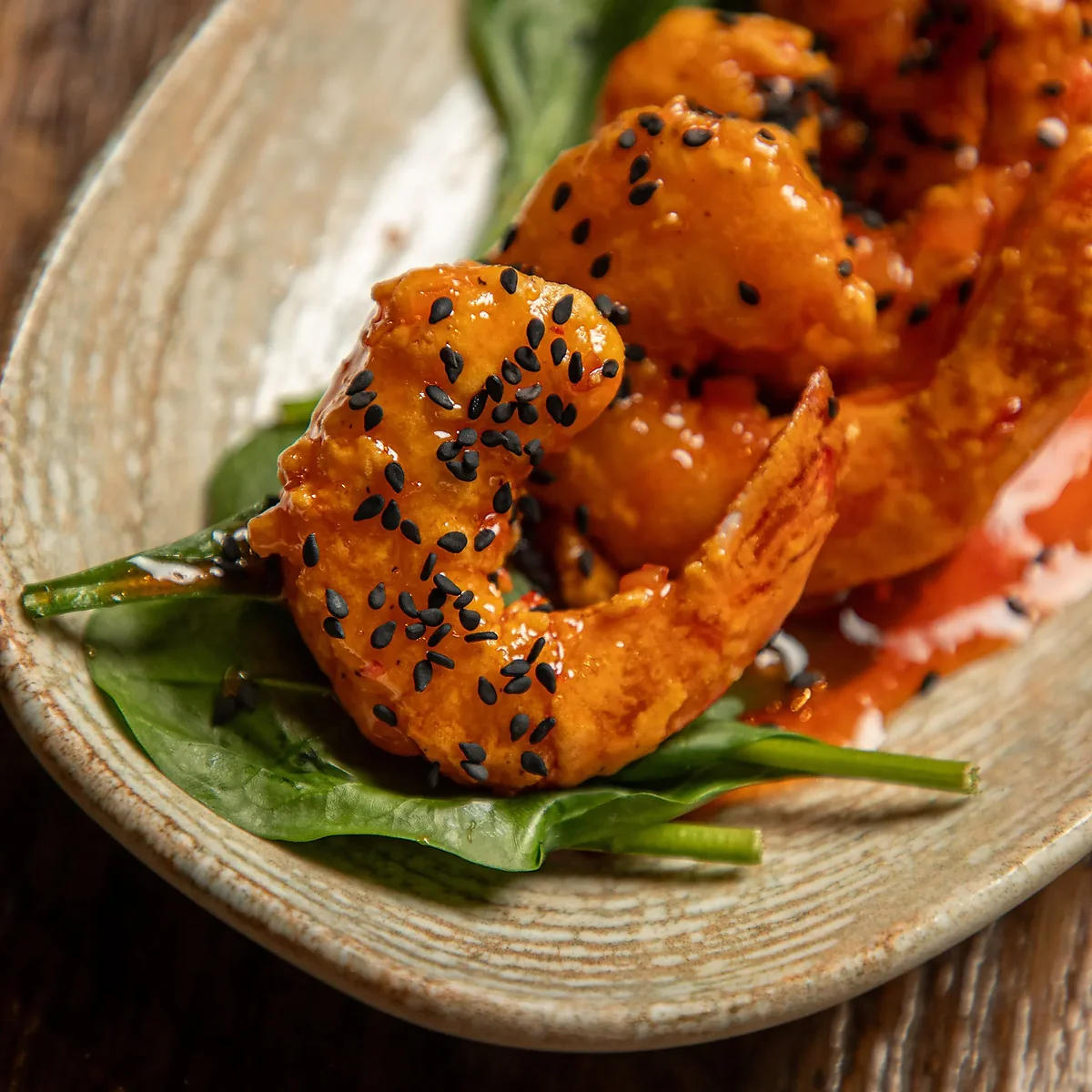 Fried shrimp in chili sauce with sesame seeds on spinach