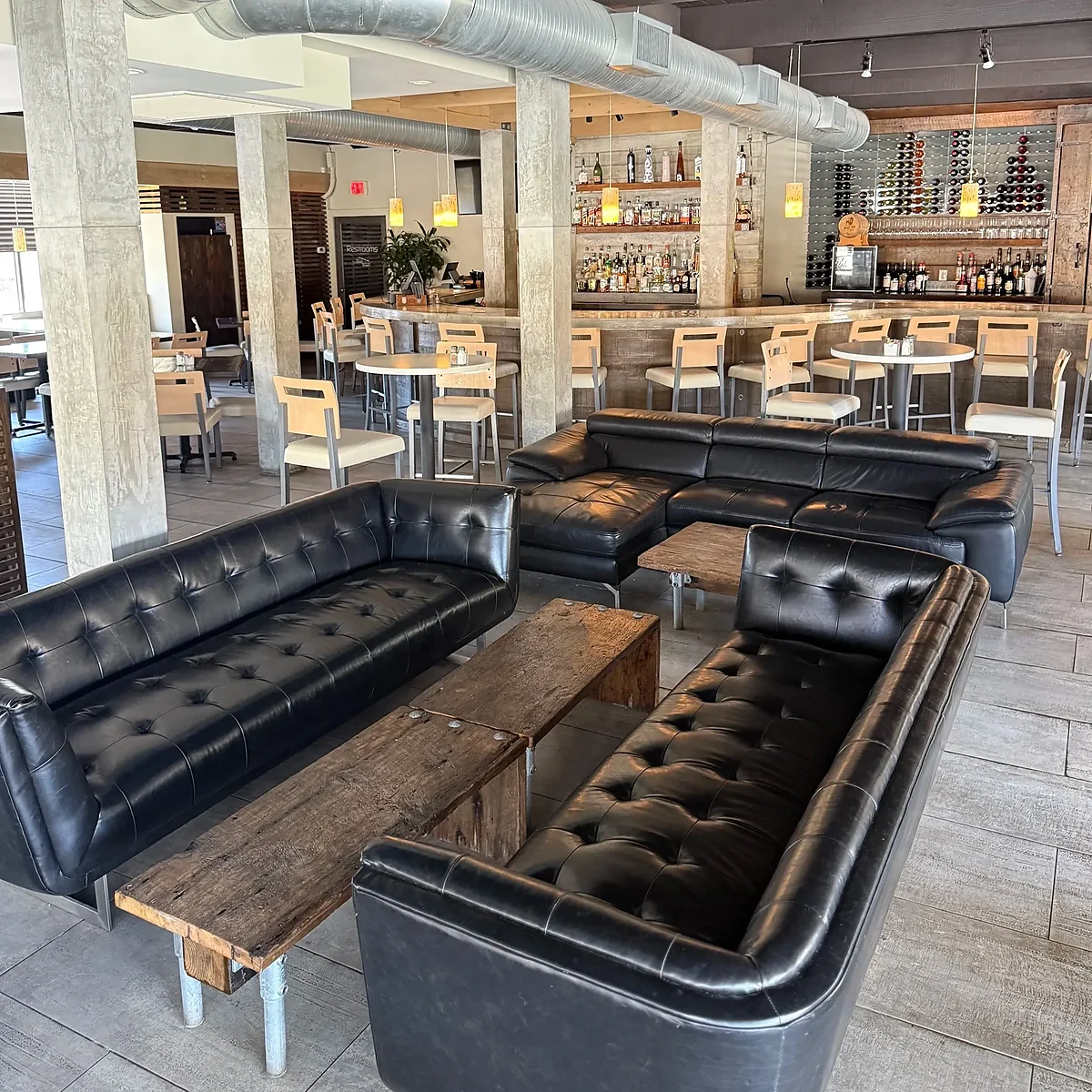 Interior lounge with black leather sofas facing the full bar