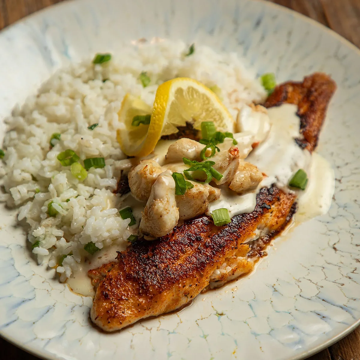 Blackened fish topped with crabmeat and cream sauce over rice