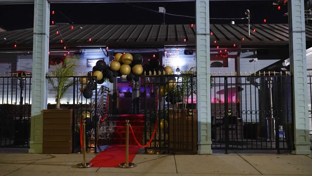 Nighttime entrance to a venue with red carpet, balloons, and lights.