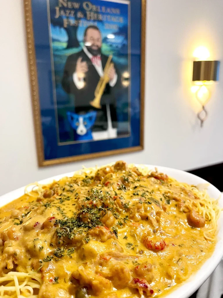 Oval plate of creamy orange pasta or étouffée, topped with herbs.