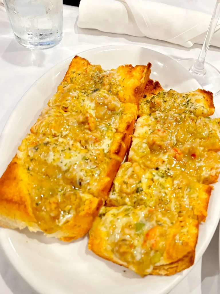 Toasted bread, melted cheese, and golden seafood topping with herbs.