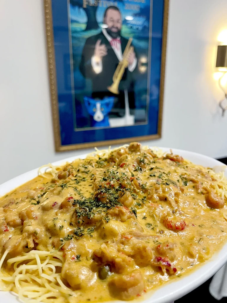 Creamy crawfish pasta with red peppers and herbs on a white plate.