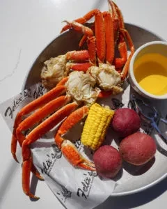 Cooked crab legs meal with corn, potatoes, and melted butter.