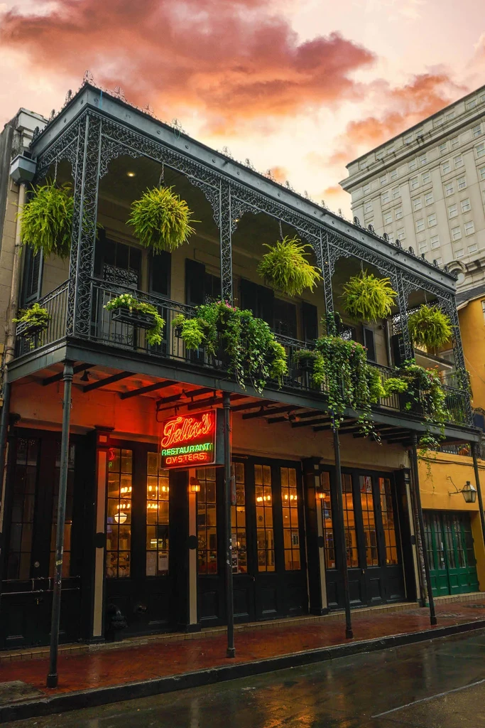 Felix's Restaurant Oysters sign glows on a plant-adorned building and wet street.
