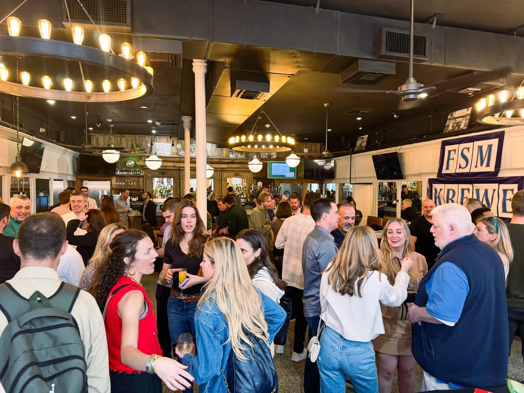 Interior of a lively bar with many people engaged in conversation.
